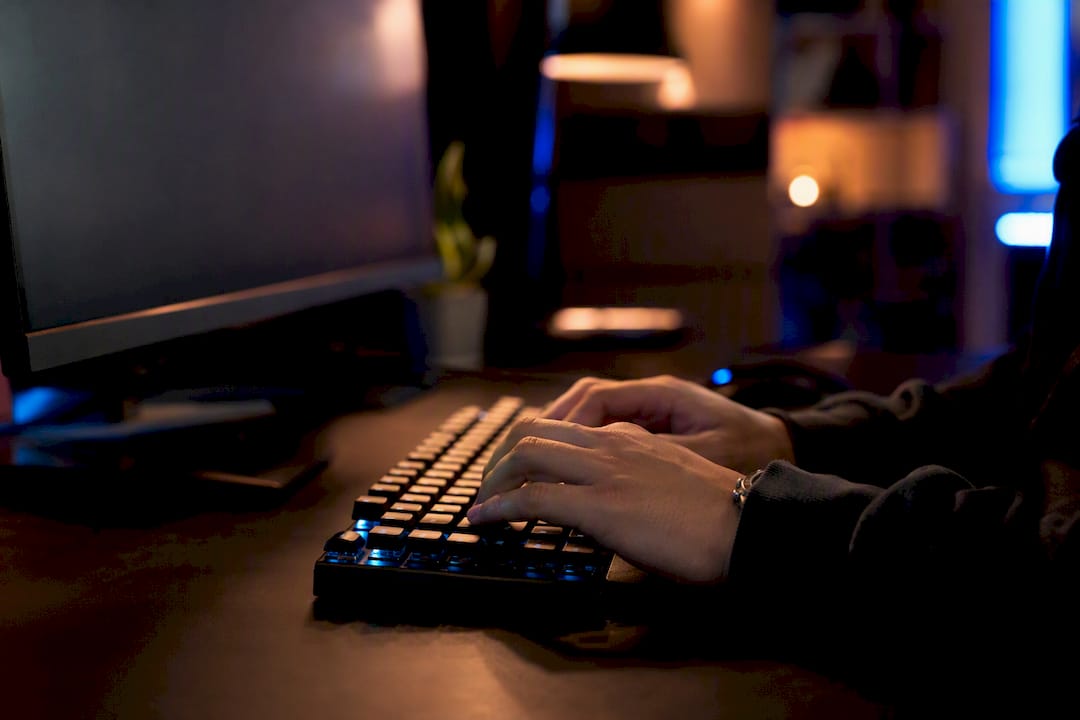 Hands typing code on dark keyboard
